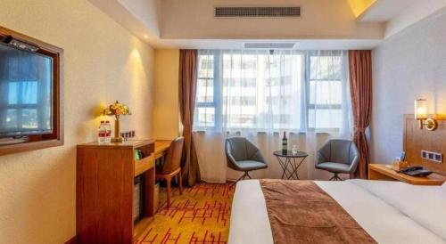 a hotel room with a bed and a desk and chairs at James Joyce Coffetel Kunming Railway Station Huancheng Nan Road Metro Station in Kunming