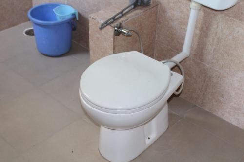 a white toilet in a bathroom with a trash can at Mysterious Kutla Cottage,Kutla, Tosh in Chhorang