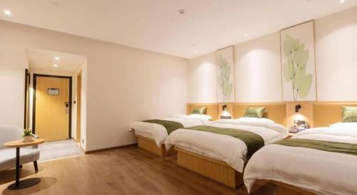 two beds in a room with white walls and wooden floors at Green Tree Inn Nanchang Zhongshan Road Bayiguan in Nanchang