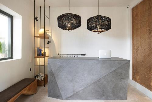 a kitchen with a concrete counter with two chandeliers at Bellonias Villas in Kamari