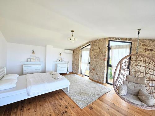 a bedroom with a white bed and a chair at Stone Villa at the Vrelo in Dobra Voda