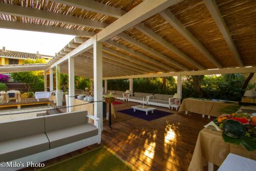 a patio with couches and tables on a wooden floor at Is Benas Country Lodge in San Vero Milis