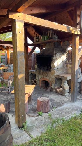a stone fireplace with a bench under a wooden roof at "Будиночок гедоніста" in Tukhlya