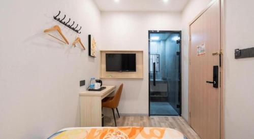 a bedroom with a bed and a desk and a television at Shell Hotel Wuxi Huishan District Chang'an Town in Wuxi