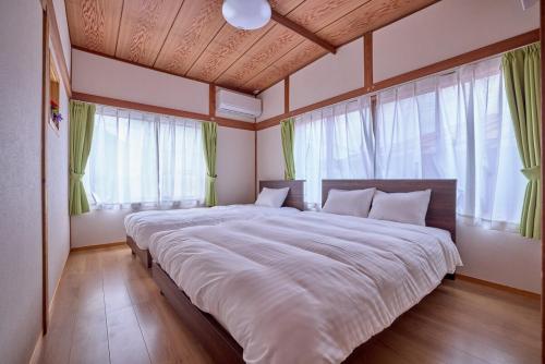 a large bed in a room with windows at APROStay富士河口湖小立17 in Fujikawaguchiko