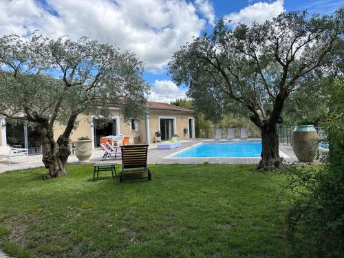 une cour avec un banc et deux arbres et une piscine dans l'établissement La Villa aux bambous, à Vézénobres