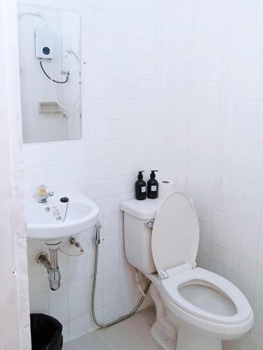 a white bathroom with a toilet and a sink at Toss Inn Hat Yai in Hat Yai