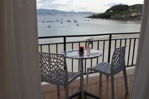 einen Tisch und Stühle auf einem Balkon mit Blick auf das Wasser in der Unterkunft Hotel Gran Proa Playa Raxó in Raxo