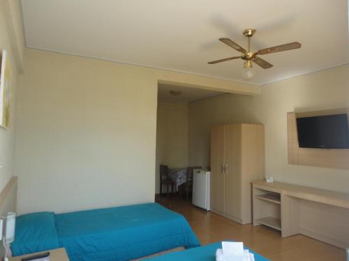 a living room with a blue couch and a ceiling fan at Jóia Hotel in Poços de Caldas