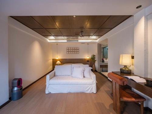 a bedroom with a white bed and a desk at Yunshang Xiyuan in Lijiang
