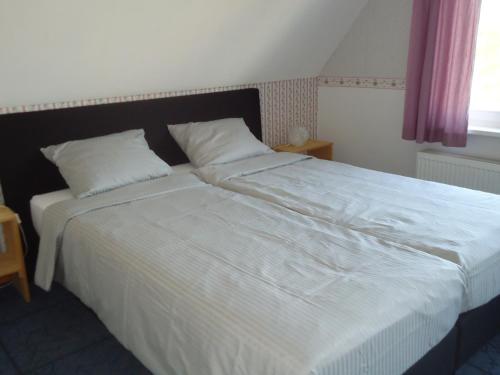 a bedroom with a large bed with white sheets at Huize Polderzicht aan het Grevelingenmeer in Battenoord