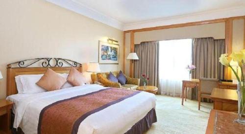 a bedroom with a large bed and a living room at Regency Hotel in Shantou