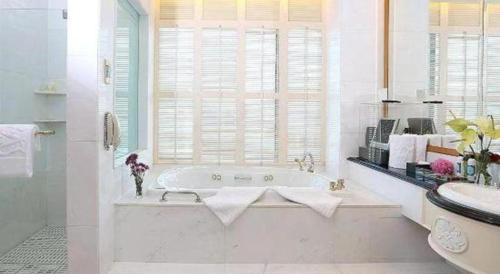 a white bathroom with a tub and a sink at Regency Hotel in Shantou