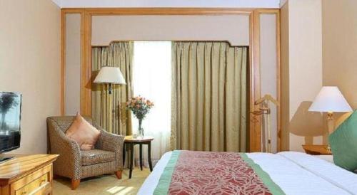 a bedroom with a bed and a chair and a television at Regency Hotel in Shantou