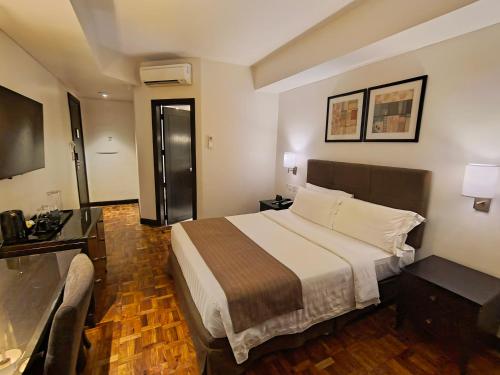 a hotel room with a bed and a television at City Garden Hotel Makati in Manila