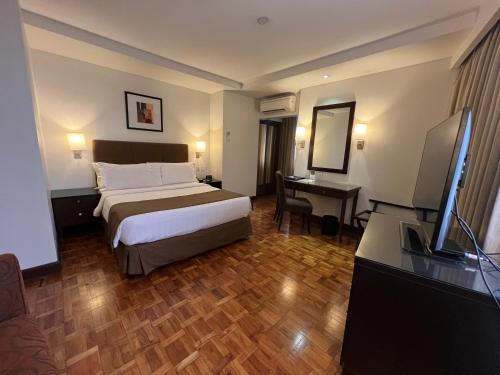 a hotel room with a bed and a desk and a television at City Garden Hotel Makati in Manila