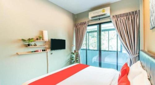a bedroom with a red and white bed and a window at OYO 726 Sookjai Cafe and Hostel in Chiang Mai