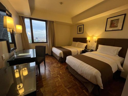 a hotel room with two beds and a window at City Garden Hotel Makati in Manila