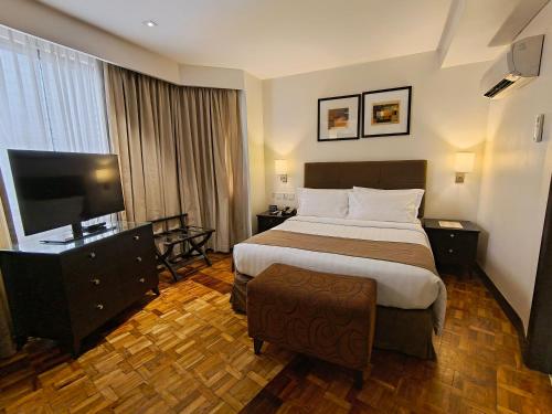 a hotel room with a bed and a flat screen tv at City Garden Hotel Makati in Manila
