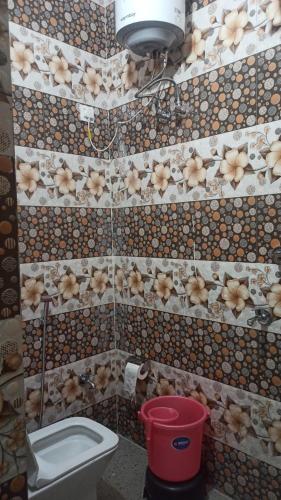 a tiled bathroom with a toilet and a bucket at Shiva home stay in Ukhimath
