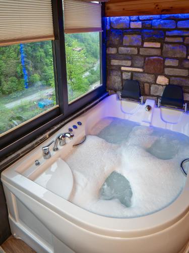 a bath tub in a room with two windows at Sisorti bungalow otel in Çamlıhemşin