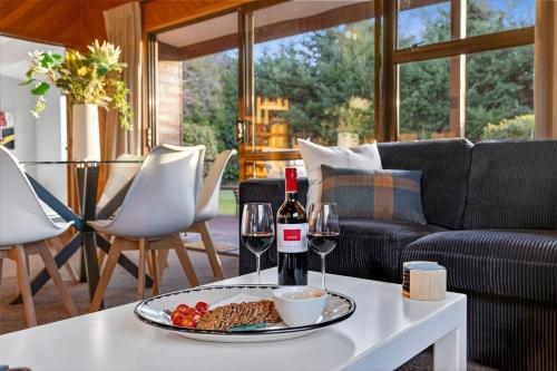 a table with a plate of food and two glasses of wine at Relaxing Retreat on Kowhai in Wanaka