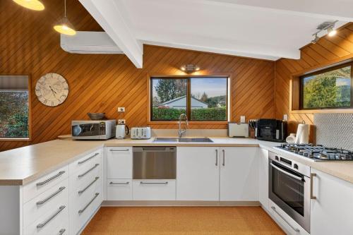 a kitchen with white cabinets and wooden walls at Relaxing Retreat on Kowhai in Wanaka