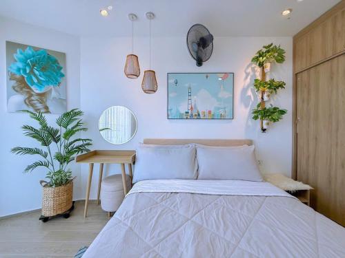 a bedroom with a bed and a table and plants at Gạo's Homestay - The Song in Vung Tau