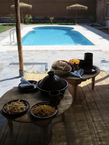 a table with food on it next to a swimming pool at Ouirgane Ecolodge in Ouirgane