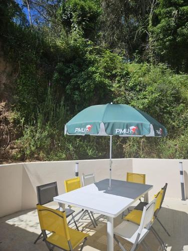 a table with a green umbrella and yellow chairs at Maison Fernand & Marie Claire in Coti-Chiavari