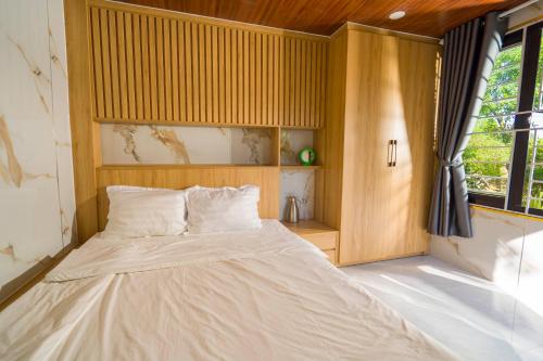 a bedroom with a bed with a wooden headboard and a window at Vân Hòa Phú Yên homestay highland in Tuy Hoa