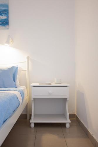 a white bed with a white nightstand next to a bed at Aurea Blu Studio 04, enjoy peace, quiet, sand and sea in Aliko Beach