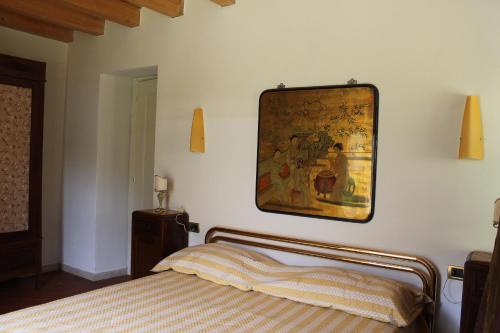 Calvagese della RivieraにあるB&B Alla Santellaのベッドルーム1室(ベッド1台付)が備わります。壁には絵画が飾られています。
