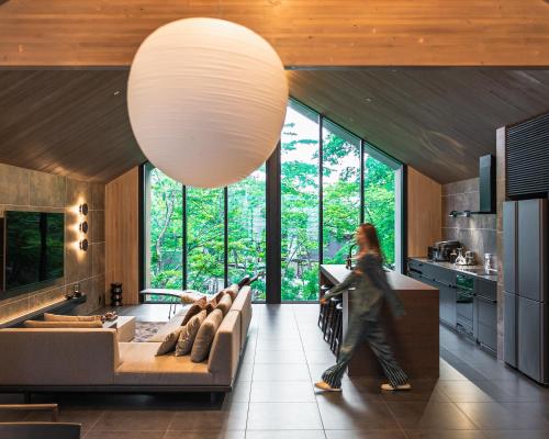 a woman walking through a living room with a couch at Hakuba Hibiku Chalet by Jade Group in Hakuba