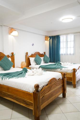 two beds in a room with blue curtains at Chair Riverside in Luang Prabang