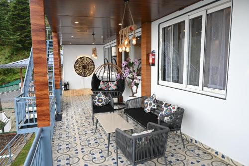 a porch with a couch and a table and chairs at Nuri By The Hills Mountain Retreat with Jacuzzi in Mussoorie