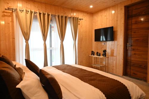 a bedroom with a bed and a tv on a wall at Nuri By The Hills Mountain Retreat with Jacuzzi in Mussoorie