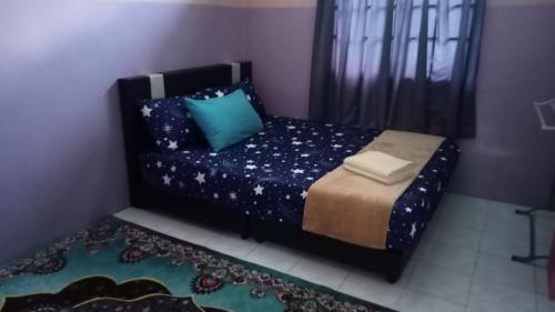 a small bedroom with a bed with blue pillows at HOMESTAY SEGAMAT - Impian Home 