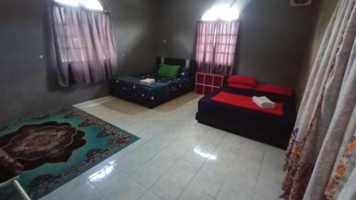 a room with two beds and a couch and windows at HOMESTAY SEGAMAT - Impian Home 