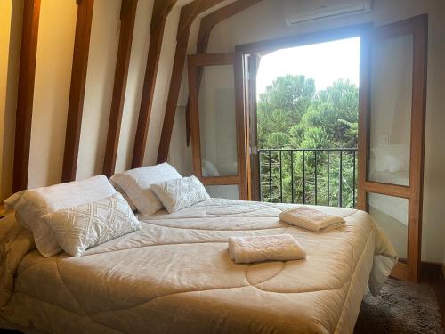 a bedroom with a large bed with a large window at Chalé Lavanda 4 km do centro Capivarí in Campos do Jordão