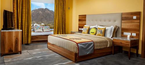 Un dormitorio con una cama grande y un televisor. en jüSTa Sajjangarh Resort & Spa, Udaipur, en Udaipur