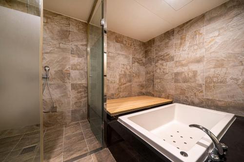 a bathroom with a tub and a shower at Busan Hound Hotel Daeyeon in Busan