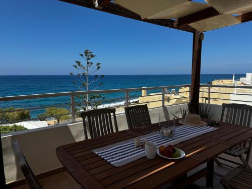 a wooden table with a plate of fruit on a balcony at Sisi Blue Seafront Apt in Sissi