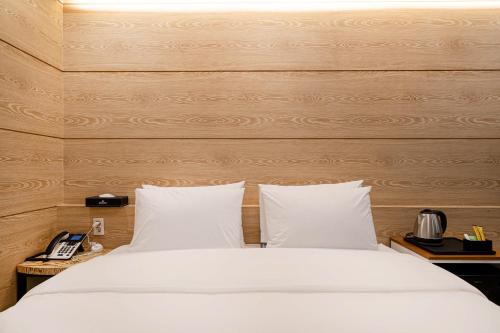 a bedroom with a white bed with a wooden wall at Busan Hound Hotel Daeyeon in Busan