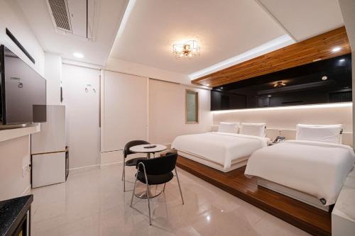 a hotel room with two beds and a table and chairs at Busan Hound Hotel Daeyeon in Busan
