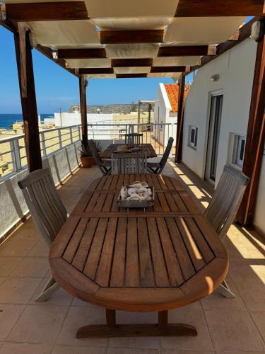 a wooden table and chairs on a balcony with the ocean at Sisi Blue Seafront Apt in Sissi