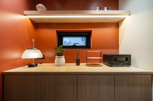 a room with an orange wall with a microwave and a tv at Busan Hound Hotel Daeyeon in Busan