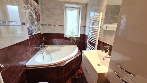 łazienka z wanną, toaletą i umywalką w obiekcie Liget Nyaralóház és Apartman Liget w mieście Szilvásvárad