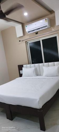 a bed with white sheets and pillows in a room at Ideal Residency in Gulbarga