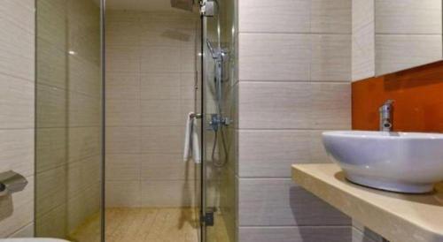 a bathroom with a sink and a glass shower at 7 Days Premium Zhuhai Gongbei Light Railway Branch in Zhuhai